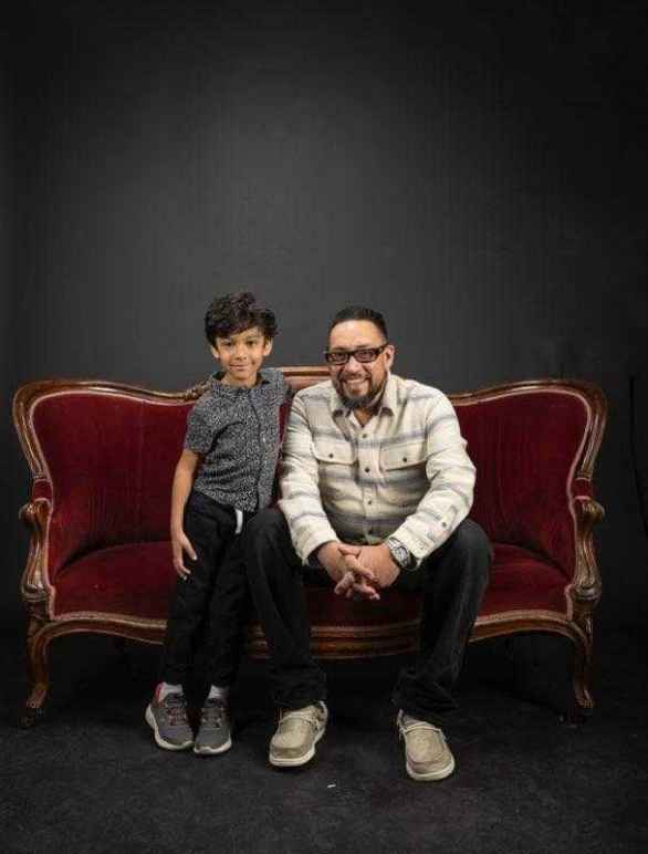 Adam Griego cuddles with his grandson on a velvet couch