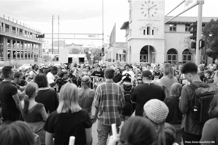 Photo: Black and white image of a group of people gathered in a circle on a street corner