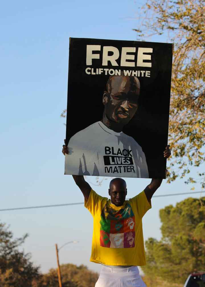 Photo of Clifton White holding a "free Clifton White" poster